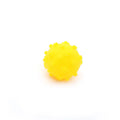 Blue, green, pink, and yellow 2-inch dog balls with spiked dimple texture on grass.