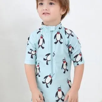 Boy's blue penguin print long sleeve swimsuit top and shorts with matching swimming cap.