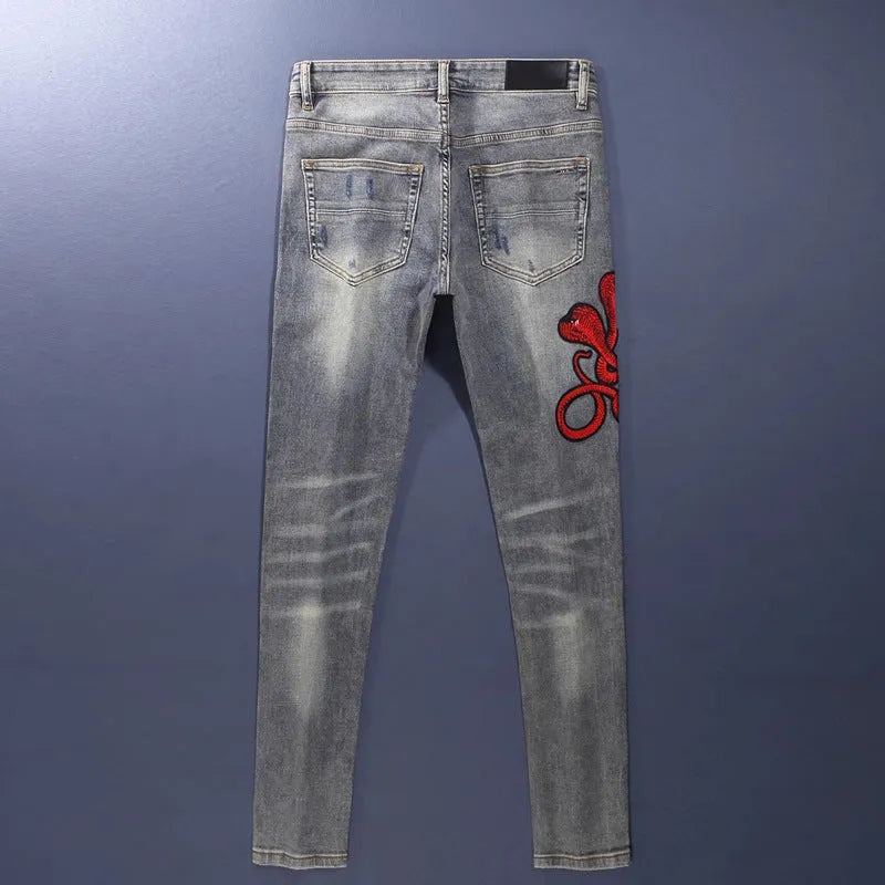 Men's slim fit jeans in old colour with a worn look, hole patches, and embroidered details on a mid-waist design.