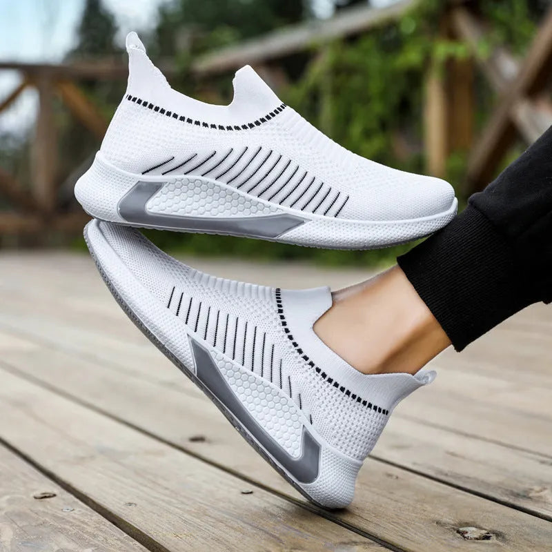 Men's black and white mesh slip-on sneakers with striped design and flat sole.