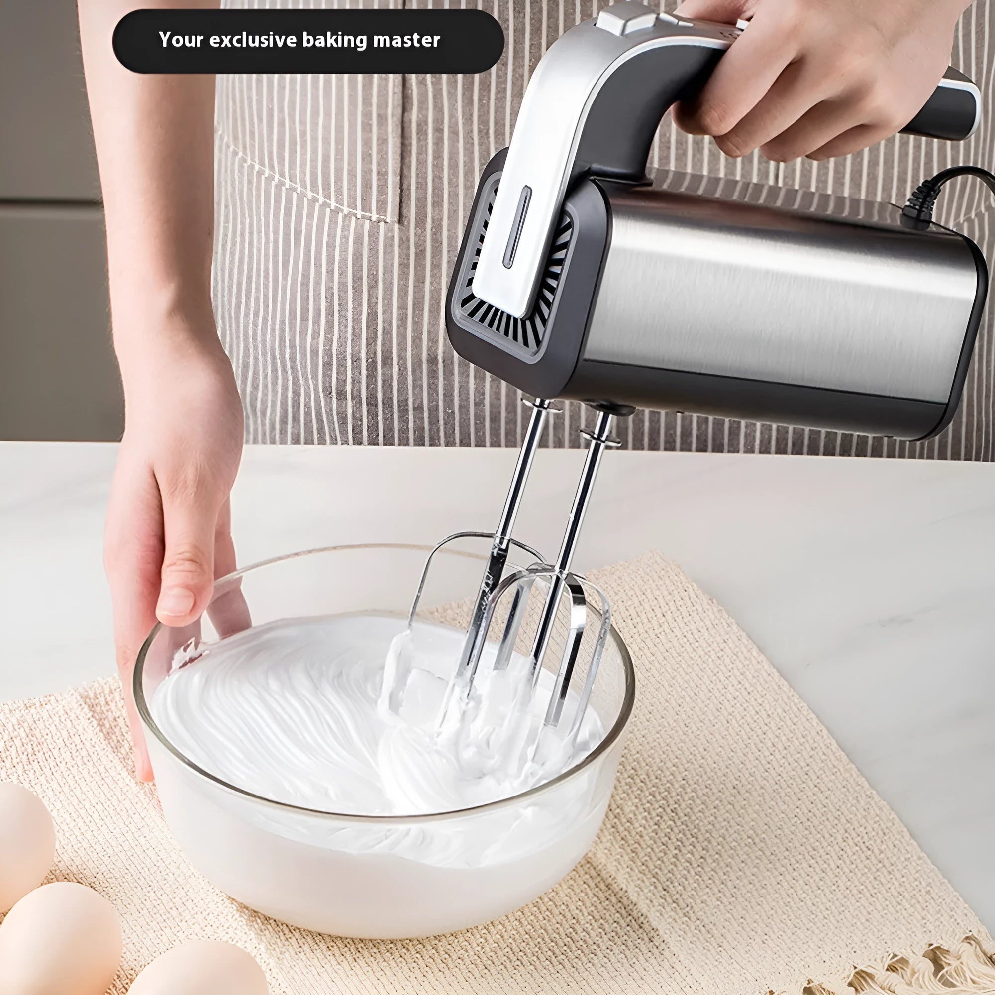 Silver mini electric hand whisk with stainless steel beaters on a kitchen counter.