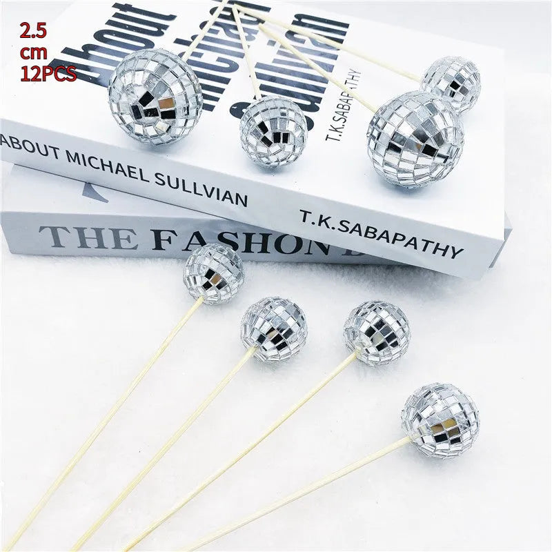 Glass disco ball cake decoration with a wooden stick inserted into a cake, showing reflective surface.