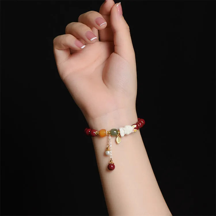 Women's natural cinnabar bracelet with a detailed rabbit pendant, shown in red.