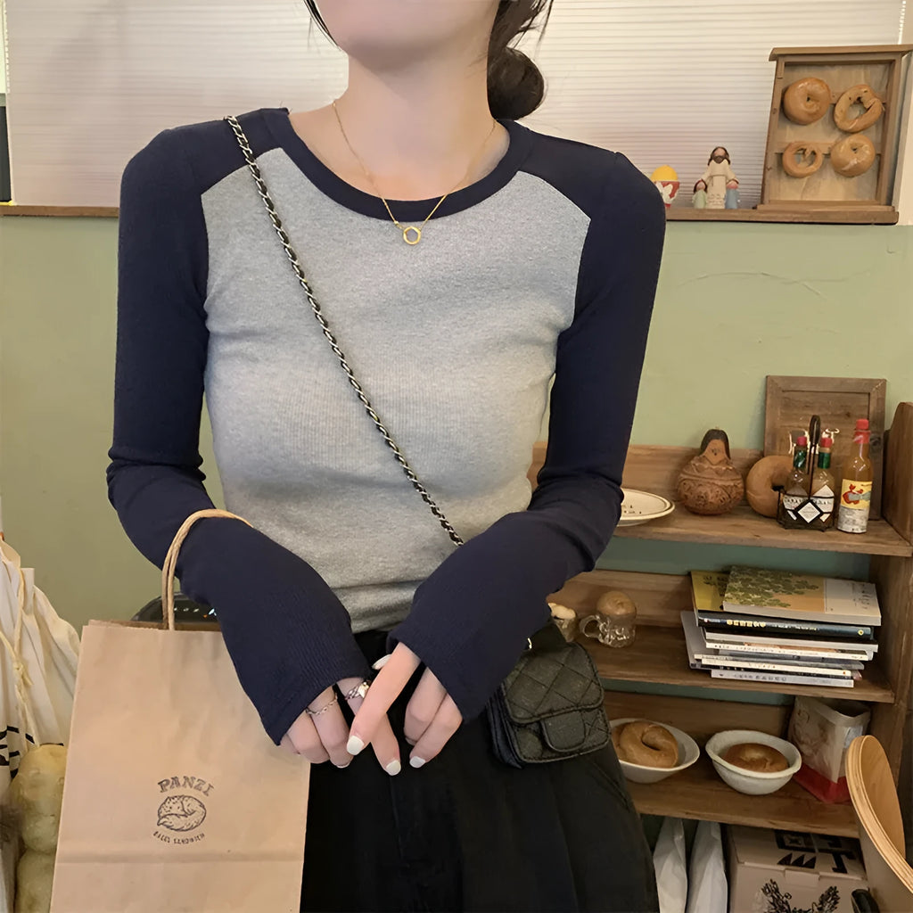 Women's black viscose top with long princess sleeves and embroidery detail on a hanger.