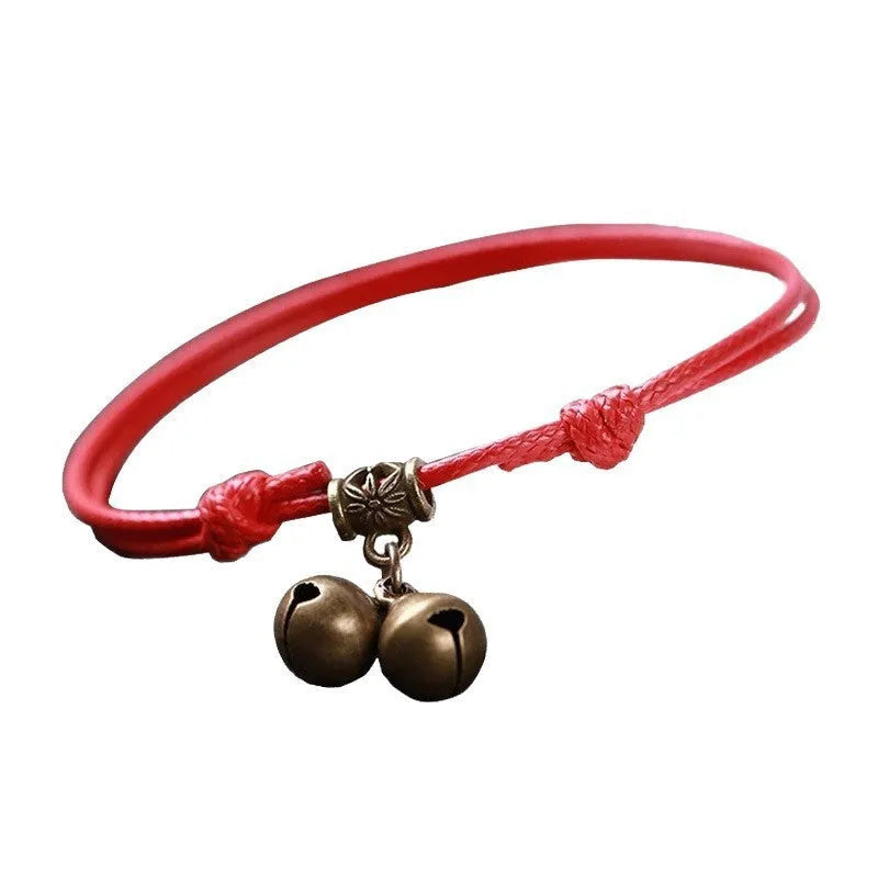 Black nylon rope dog collar with a brass bell on a wooden surface.