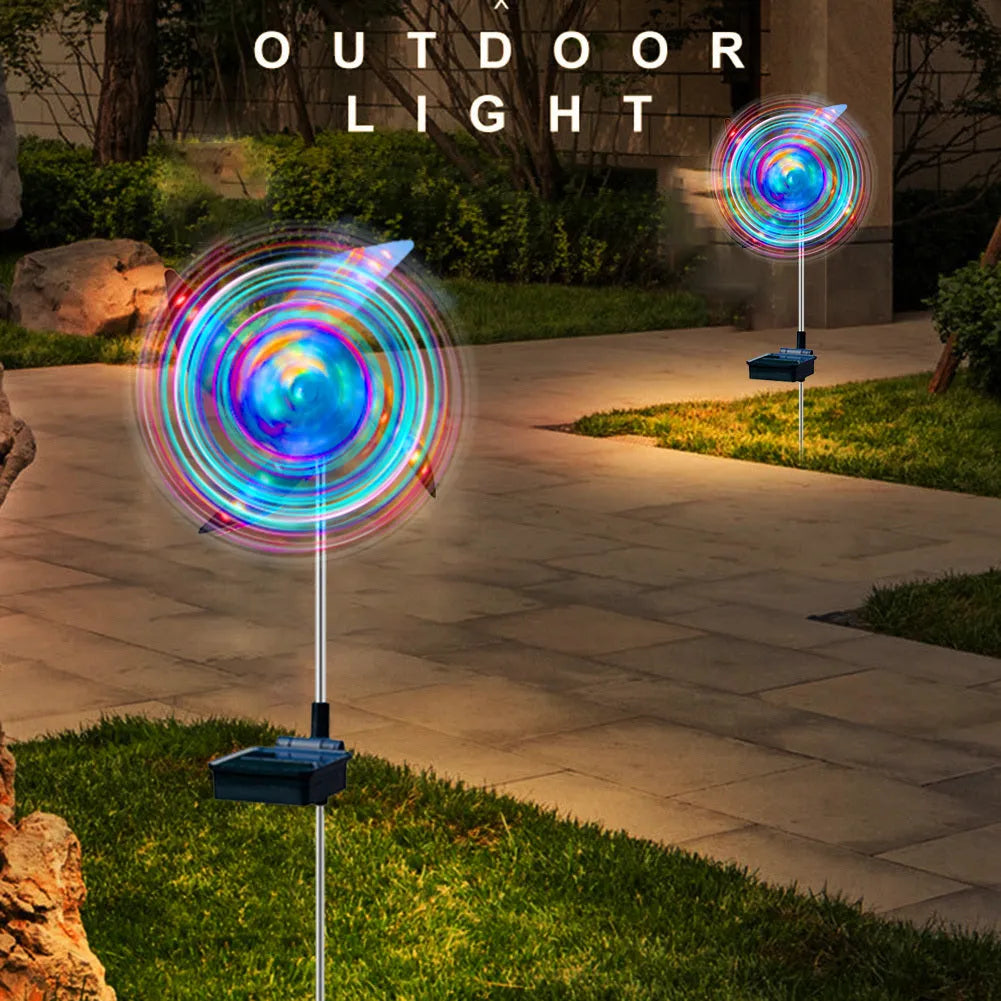 Solar wind spinner light with LED illumination spinning on lawn at dusk, showing IP65 waterproof aluminium and ABS construction