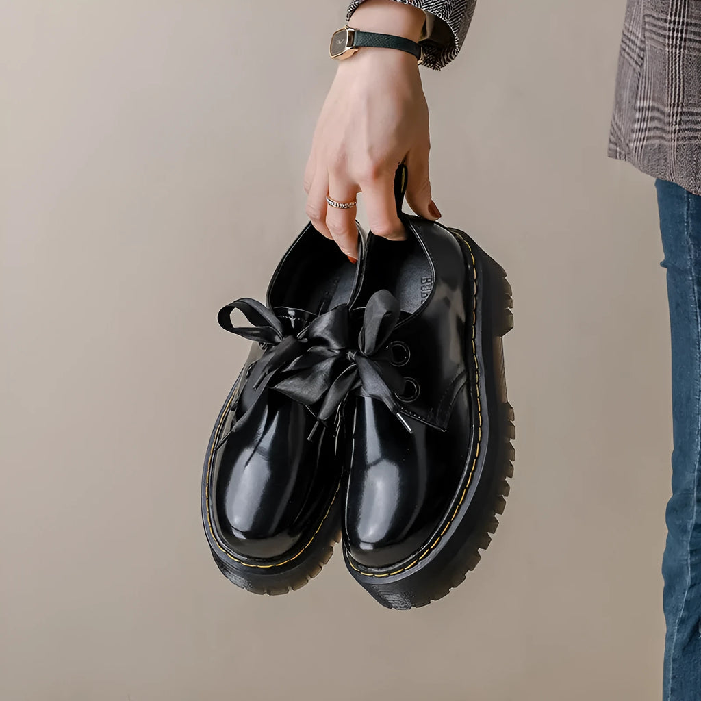 Women's thick soled leather shoes with ribbon cross straps and lace-up closure in black colour