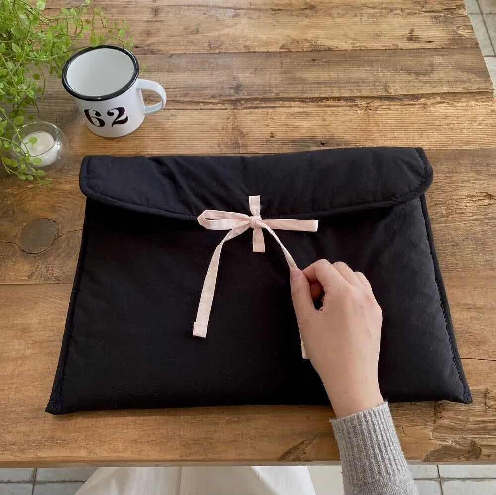 Women's black quilted laptop bag with ballet bow detailing and striped pattern showing laptop compartment