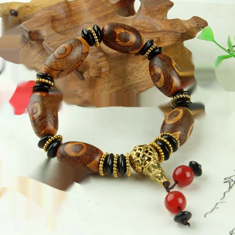 Distressed agate Tibet bead bracelet with three-eye motifs and multiple traditional bead styles on wrist