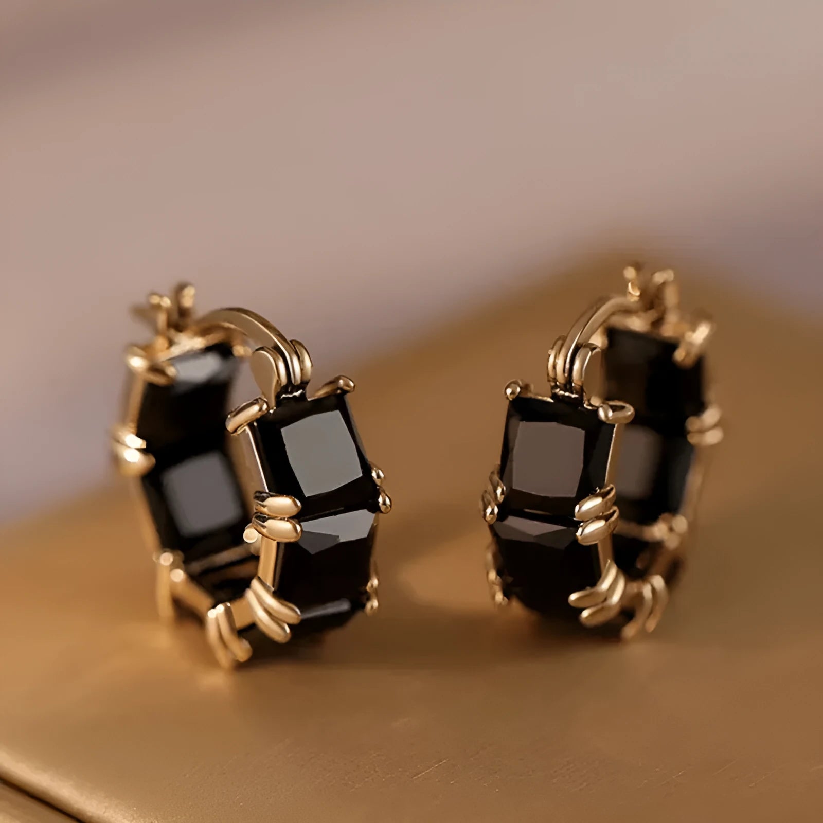 Geometric U-shaped gold earring with a round black zirconium stone on a copper base.