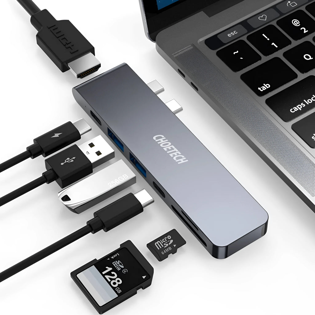 Silver 7-in-1 USB-C hub adapter with SD card reader, HDMI, and USB ports on a wooden desk.