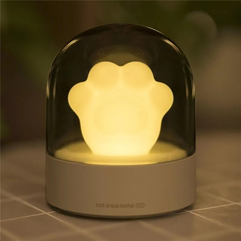 Grey and pink cat paw shaped USB rechargeable night light with music box on a desk
