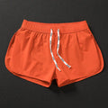 Men's loose orange polyester beach shorts on a hanger against a neutral background