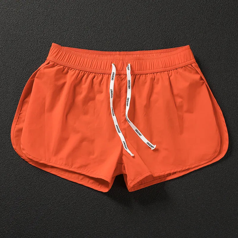 Men's loose orange polyester beach shorts on a hanger against a neutral background