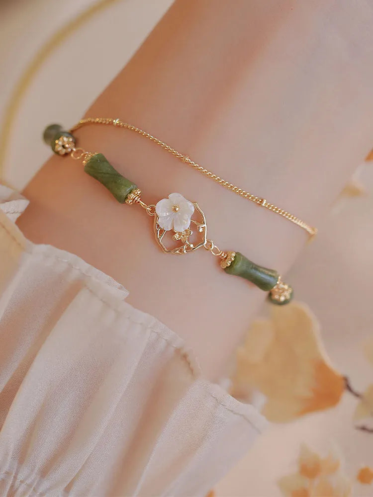 Handmade natural olivine bracelet with double layer design and Bells of Ireland charms on a wrist.