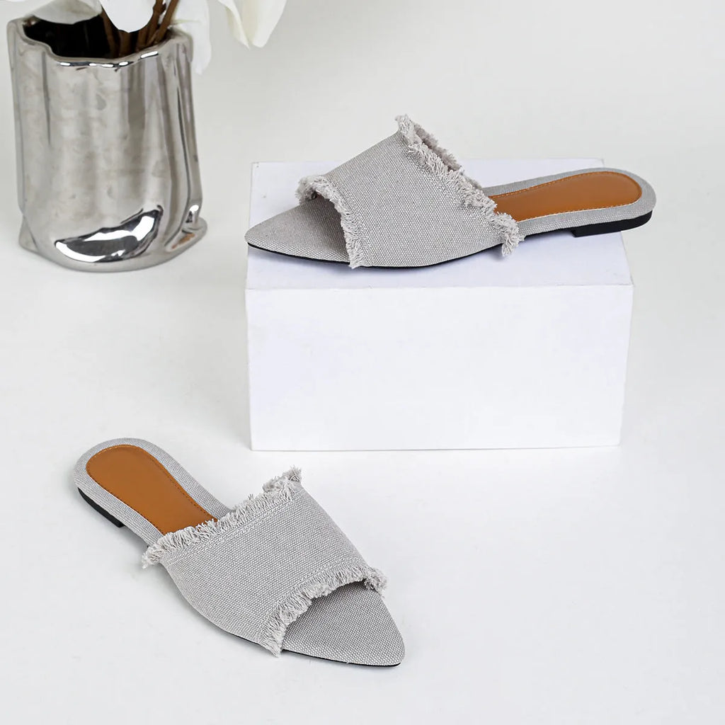 Women's denim flat slippers with a tassel, leather lining, and a lightweight PVC sole.