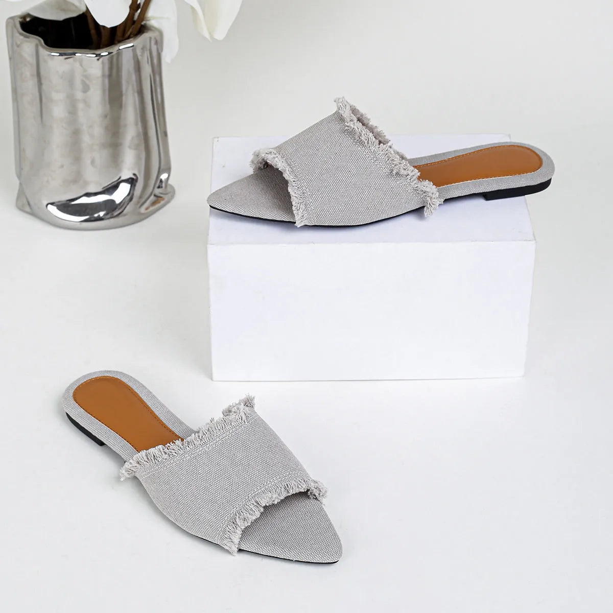 Women's denim flat slippers with a tassel, leather lining, and a lightweight PVC sole.