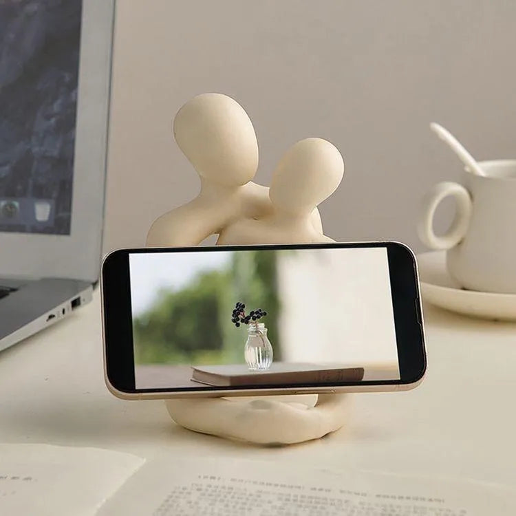 Modern loving couple resin statue in gold or milky white finish on a wooden desk.