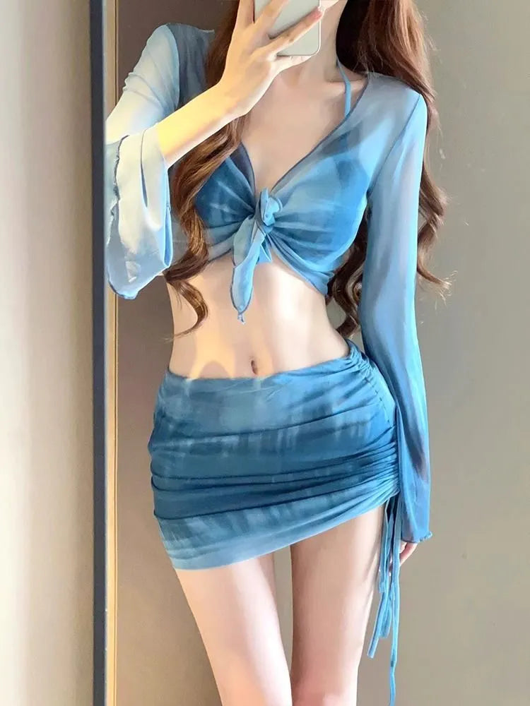 Women's blue four-piece bikini swimsuit set showing high-waisted briefs and coordinating shirt and skirt components