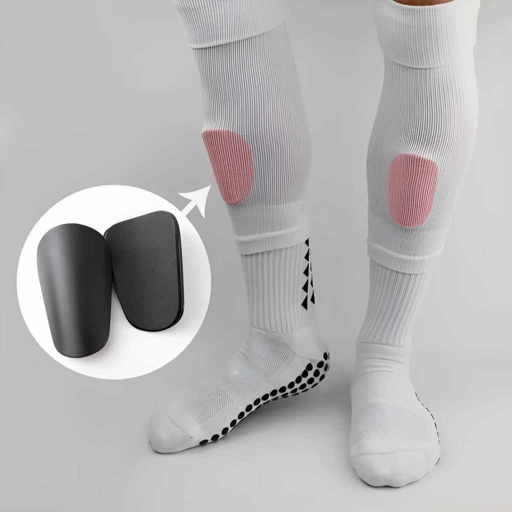 Pair of PU mini shin guards in black with adjustable straps, shown on a leg.