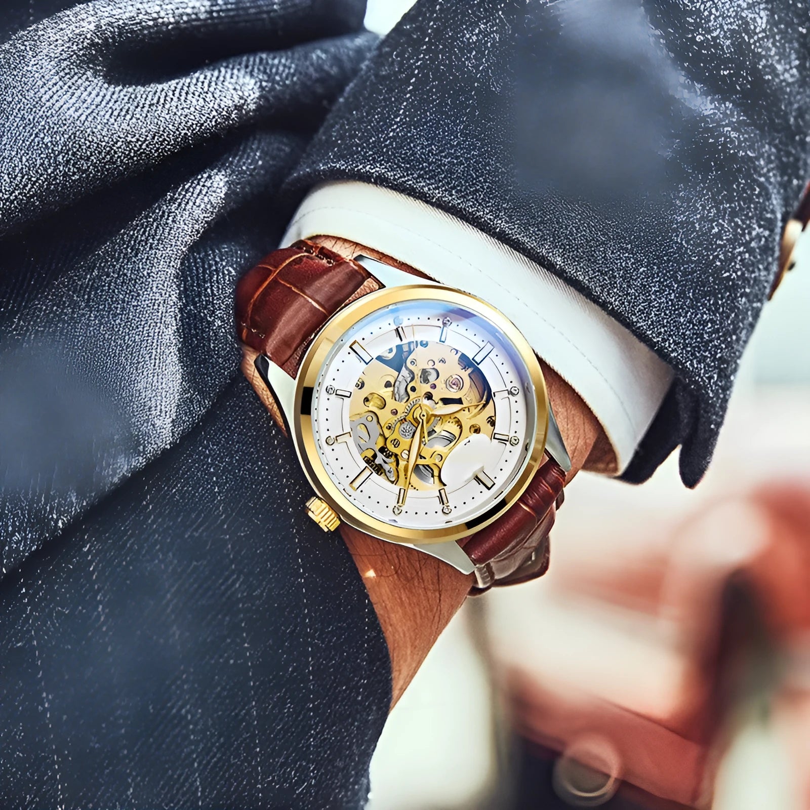 Gold shell mechanical watch with brown leather strap and white dial on a wrist