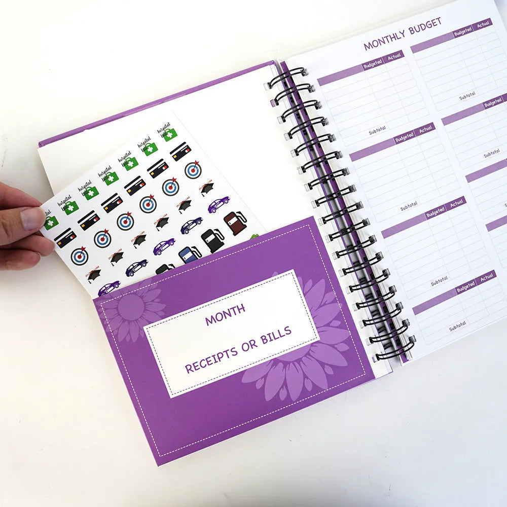 Purple coil-bound financial planning notebook with budgeting stickers and pen on Daolin paper