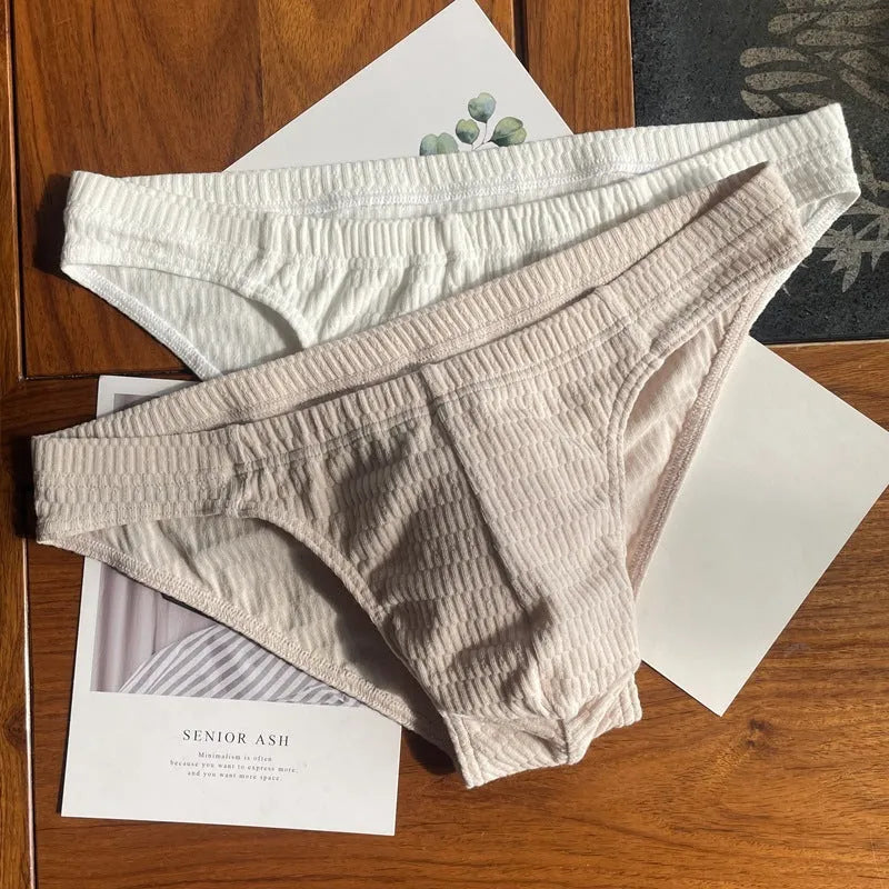 Men's solid colour cotton triangle underwear briefs laid flat, showing mid-waist design in apricot, black, skin colour and white options.