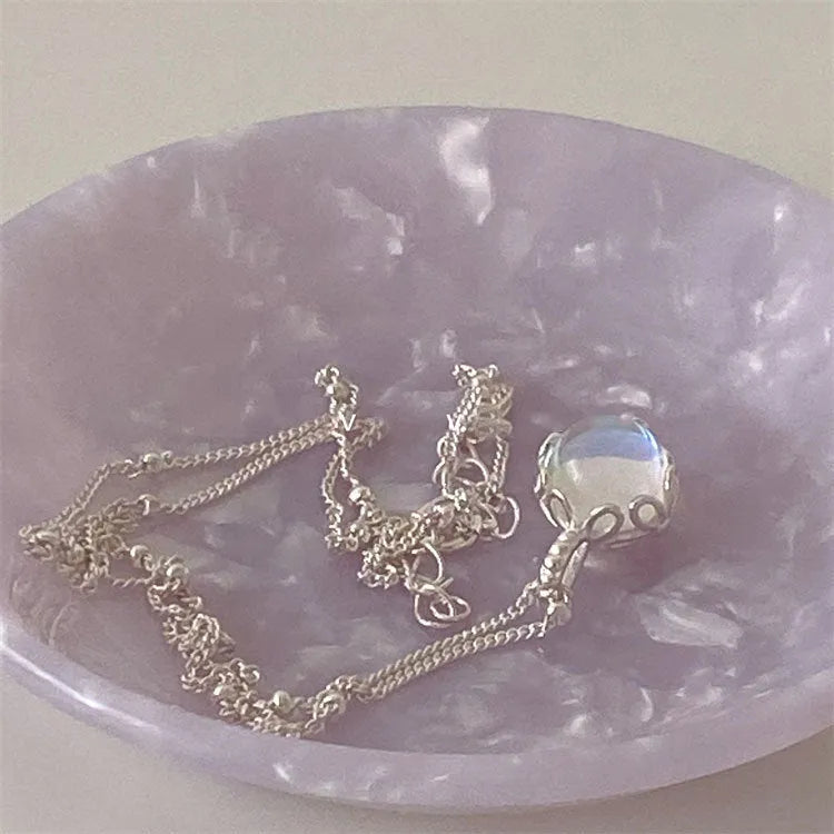 Women's silver necklace with large round geometric stone pendant on a curb chain.