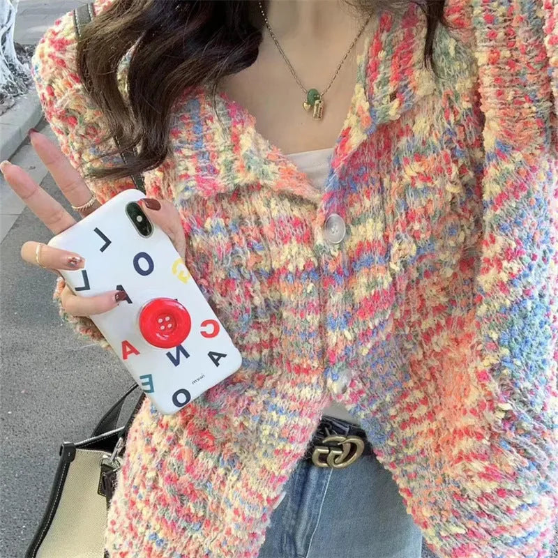 Pink and green retro rainbow patterned knitted cardigan sweater on a hanger.