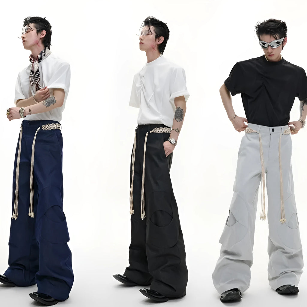 Men's dark blue straight-leg jeans showing heavy 3D stitching and tassel pocket decoration.