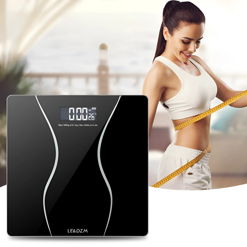 Black electronic digital bathroom scale with LCD display on a bathroom floor.