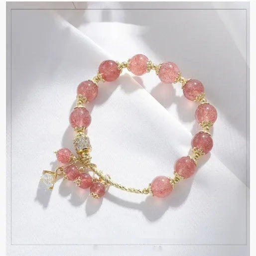 Pink heart-shaped strawberry quartz and pearl women's bracelet on a wrist.