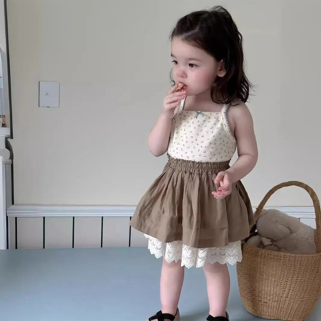 Baby girl wearing floral camisole vest and brown cotton skirt with dots pattern on a white background