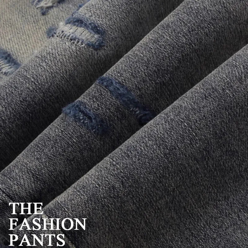 Men's slim fit jeans in old colour with a worn look, hole patches, and embroidered details on a mid-waist design.