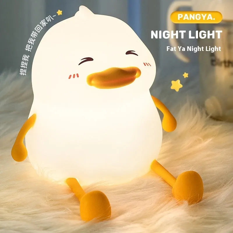 Chubby silicone and plastic night light on desk holding a mobile phone with soft LED glow.