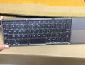 Ultra-thin tri-fold folding Bluetooth keyboard with touchpad shown in black and silvery white colours