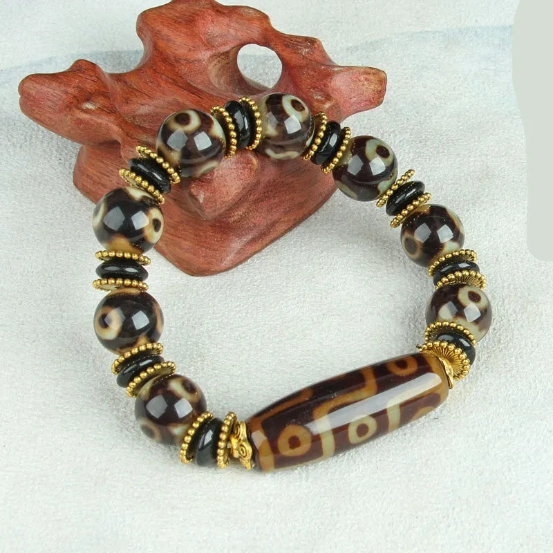 Distressed agate Tibet bead bracelet with three-eye motifs and multiple traditional bead styles on wrist
