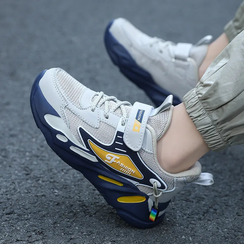 Boys' blue and black platform sports running shoes with Velcro strap on a hard ground surface.