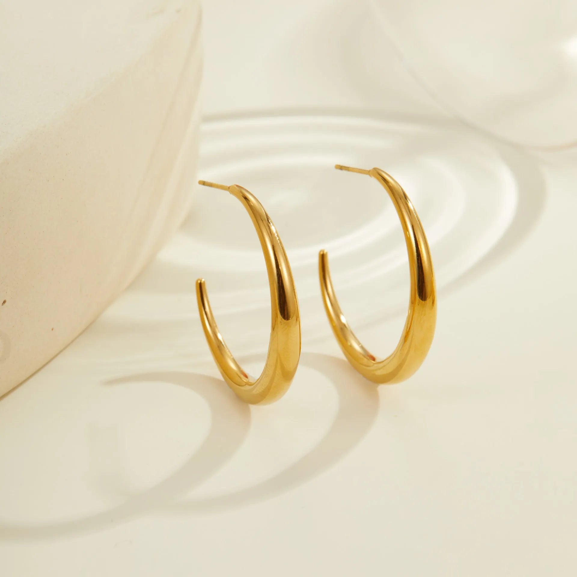 Titanium steel hoop earrings in gold and steel finishes, available in large and small sizes with simple geometric design