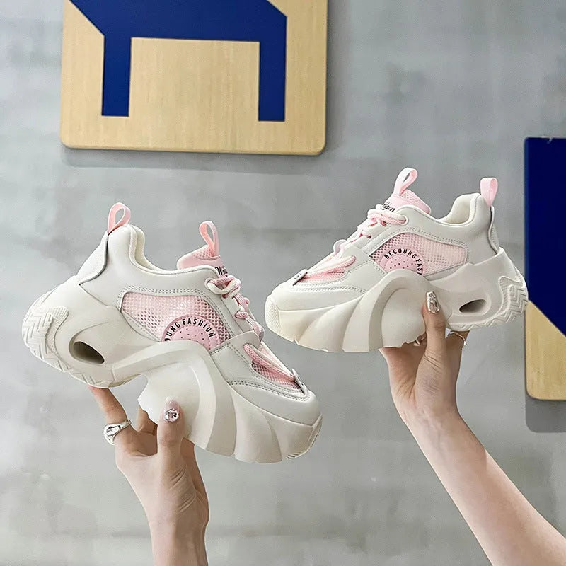 Women's pink platform sneakers with a thick sole and cross ankle straps on a white background.