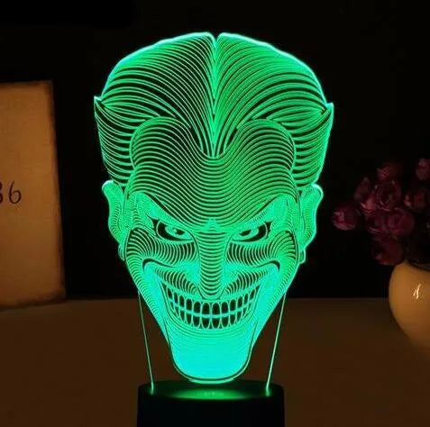 A 3D LED table lamp with a colourful acrylic panel on a square base, showing multiple colour options.