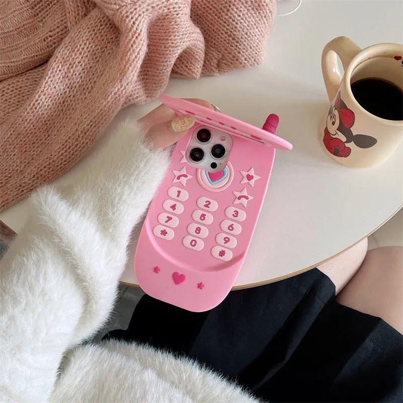 Light pink silicone flip phone shape case with mirror for iPhone, showing cute cartoon style.