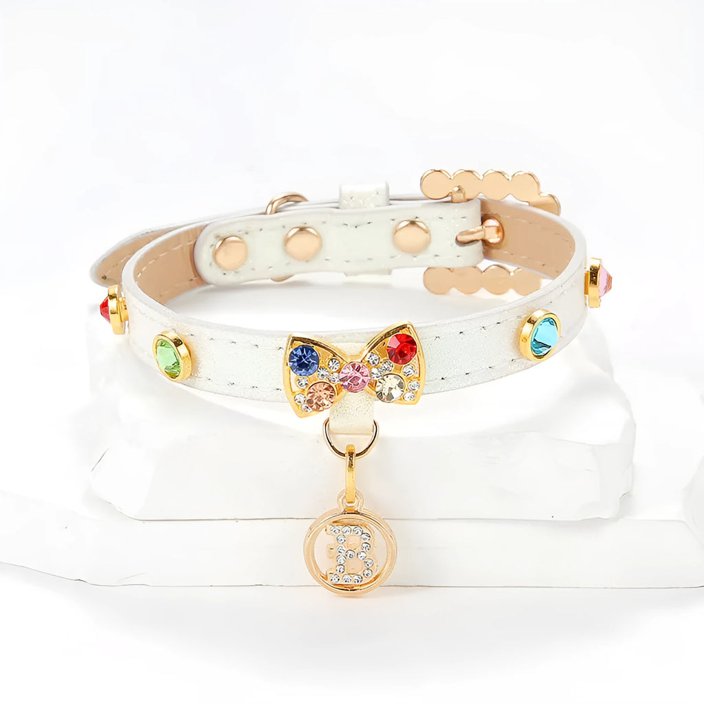 White PU leather cat collar with diamond alloy bow displayed on a surface, showing buckle and adjustable length