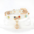 White PU leather cat collar with diamond alloy bow displayed on a surface, showing buckle and adjustable length