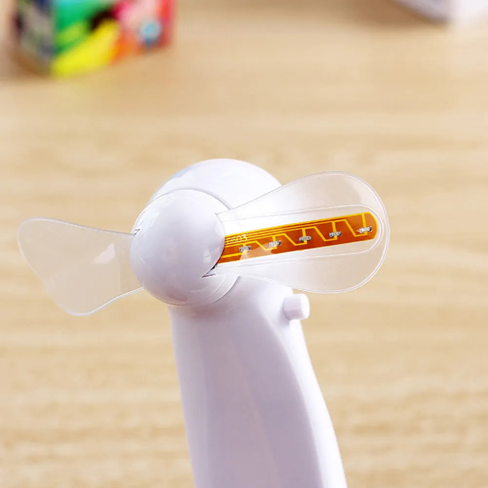 White handheld mini fan showing blue and red LED 'I love you' pattern flashing on front.