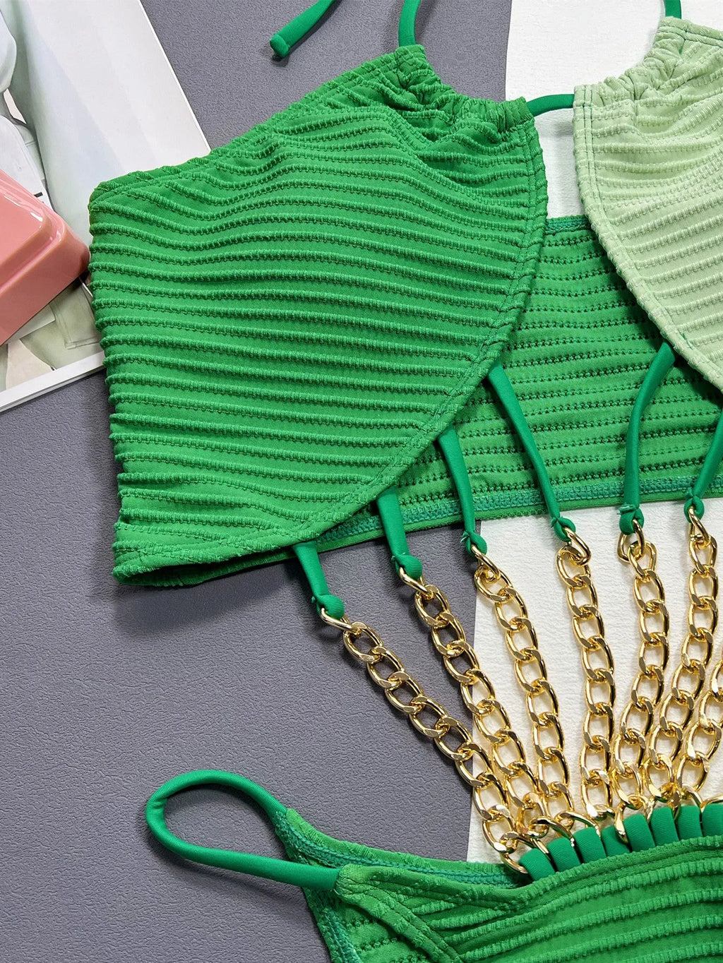 Green women's one-piece swimsuit with a hollow design on a solid colour background.