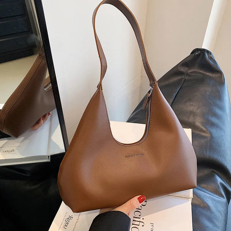 Brown retro PU leather shoulder handbag with a single strap and pillow-shaped design on a plain background.
