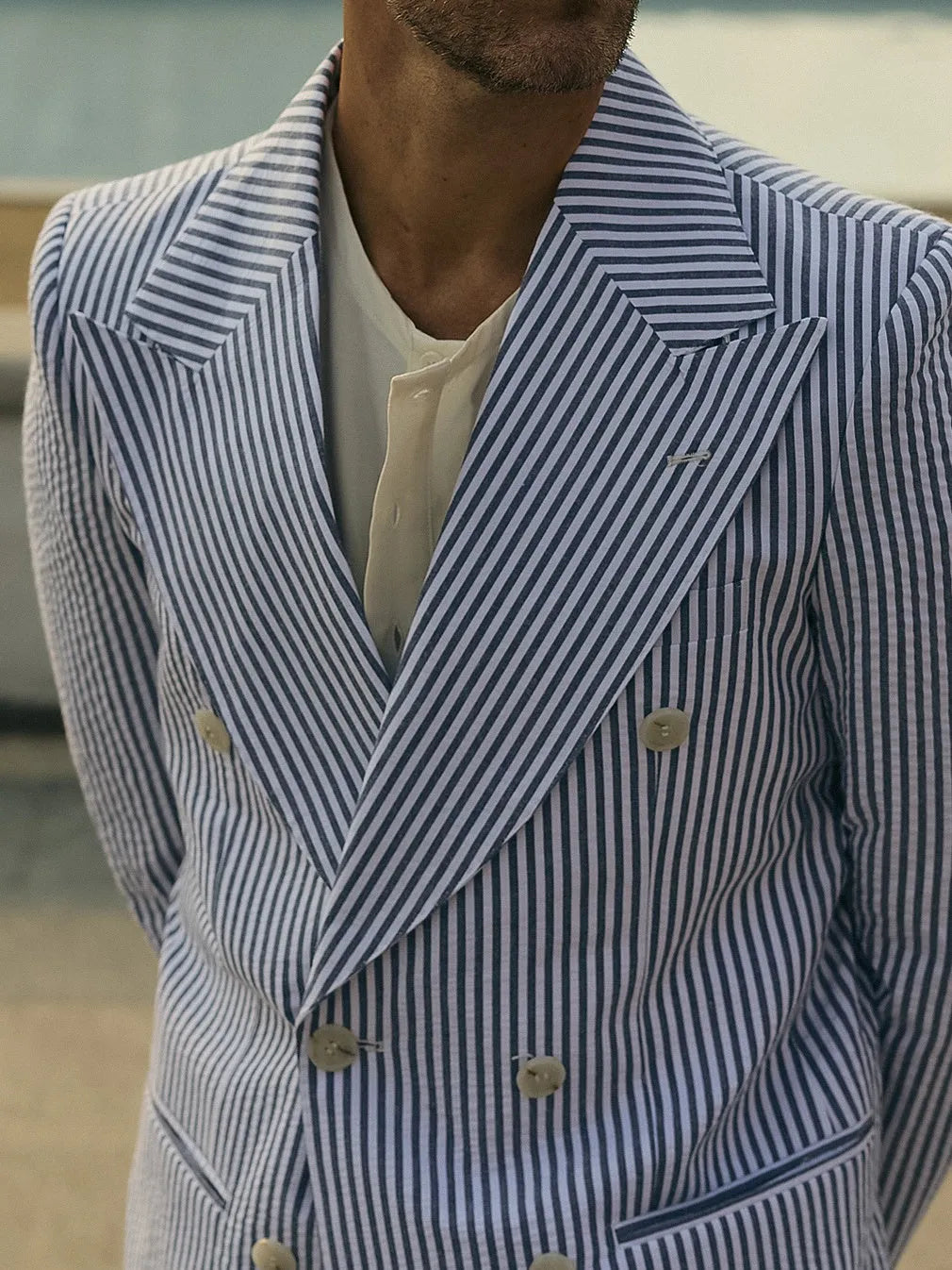 Blue and white striped polyester suit set with blazer and trousers on hanger