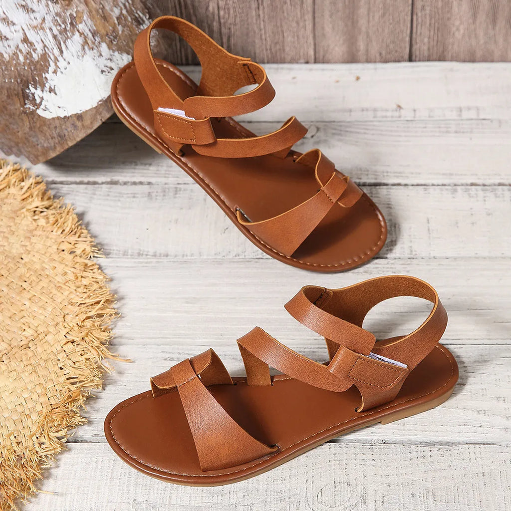 Women's flat sandals with Velcro strap, round toe, and rubber sole in black, brown, and multicolour.