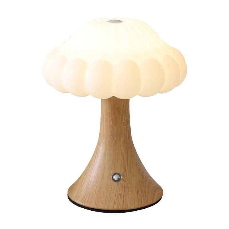 Mushroom-shaped touch control night light in cream colour on a wooden table.
